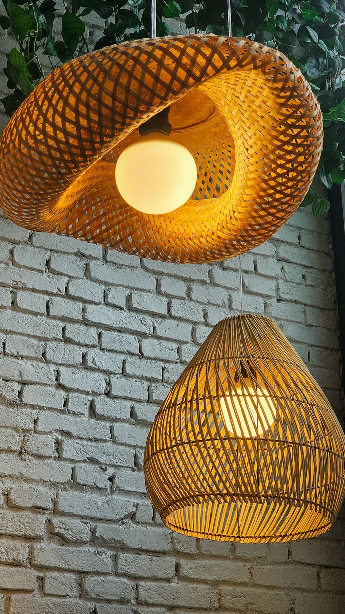 Stylish rattan pendant lights illuminate a white brick wall with a modern and artistic touch.