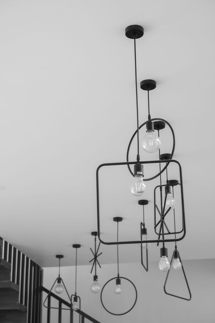 Black geometric chandelier with exposed bulbs in a minimalist room, creating an artistic vibe.