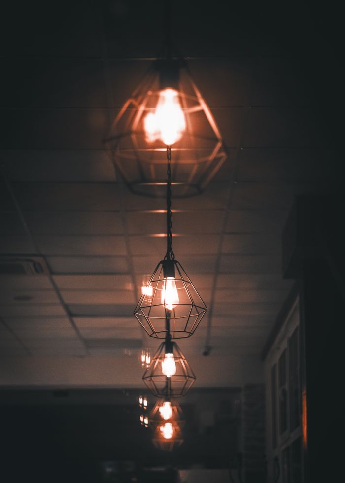 Home Warm illuminated pendant lights casting shadows in a dark room, creating a modern ambiance.